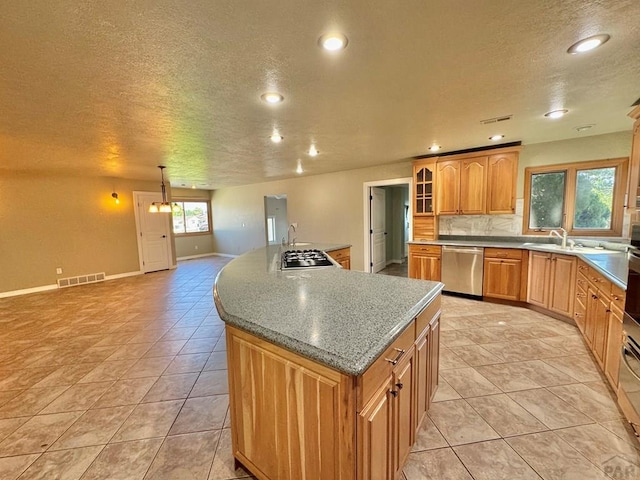 kitchen with light countertops, visible vents, stainless steel dishwasher, glass insert cabinets, and a kitchen island