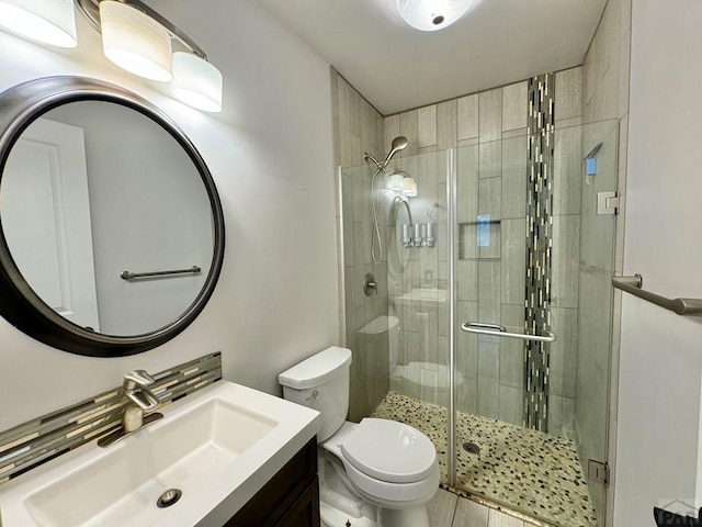 bathroom featuring toilet, a stall shower, and vanity