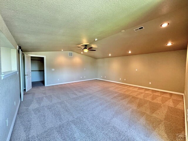 carpeted empty room featuring lofted ceiling, ceiling fan, visible vents, and recessed lighting