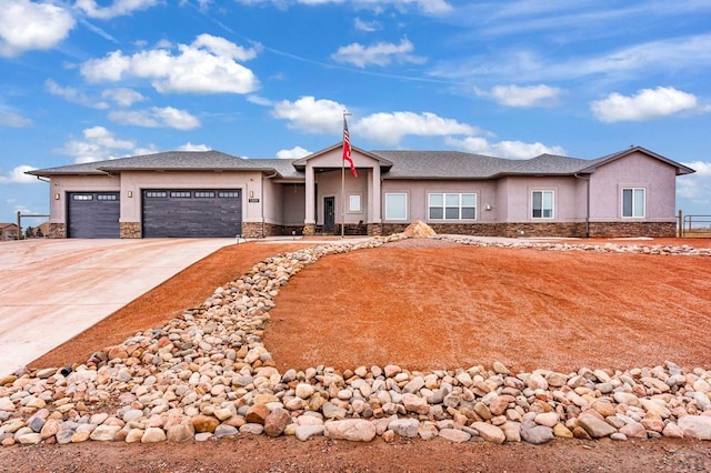 view of front facade featuring a garage, stone siding, driveway, and stucco siding