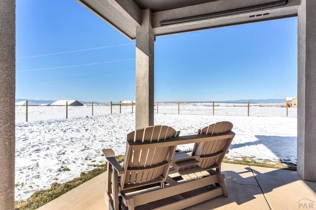 snow covered patio featuring a fenced backyard