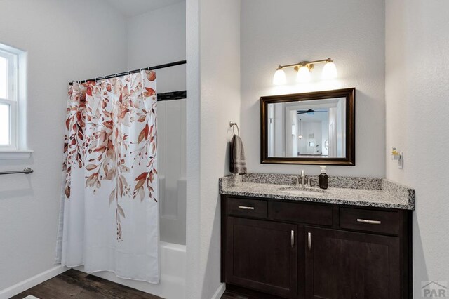 full bath with shower / bath combination with curtain, vanity, baseboards, and wood finished floors