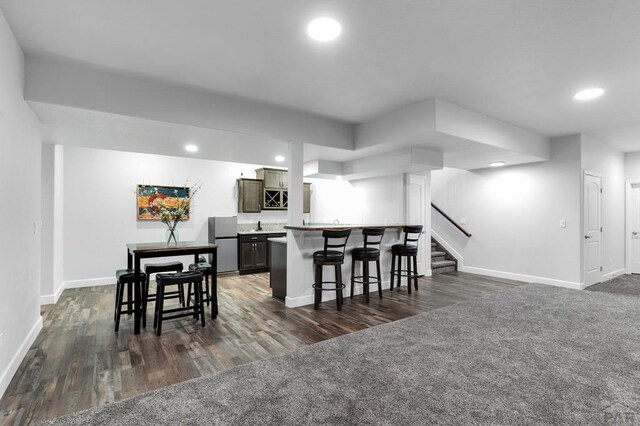 kitchen featuring freestanding refrigerator, light countertops, a kitchen bar, and recessed lighting