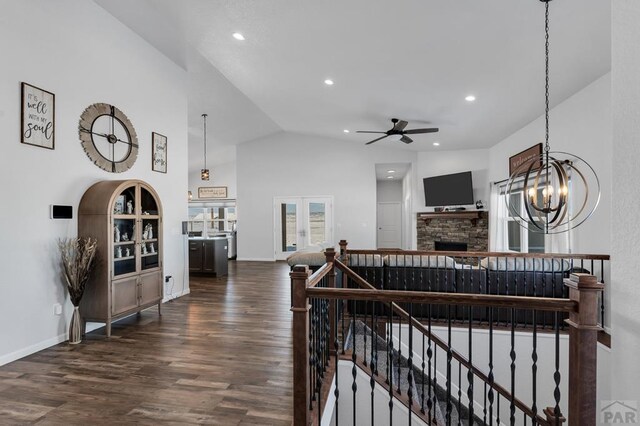 living room featuring dark wood finished floors, french doors, lofted ceiling, a stone fireplace, and recessed lighting