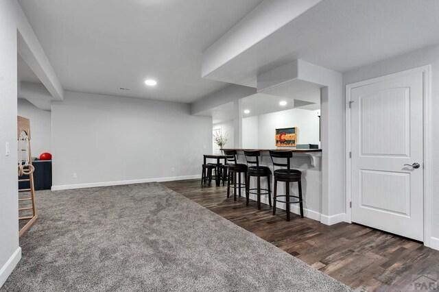 interior space with baseboards, a kitchen breakfast bar, and dark wood finished floors