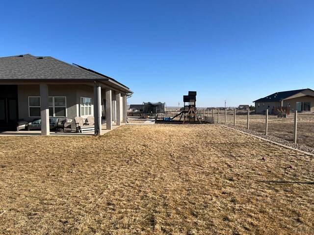 view of yard with a playground, fence, and a patio