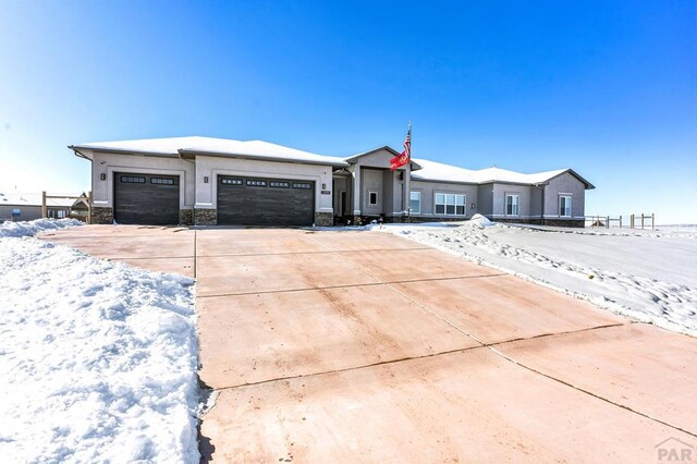 view of front of property featuring stone siding, concrete driveway, an attached garage, and stucco siding