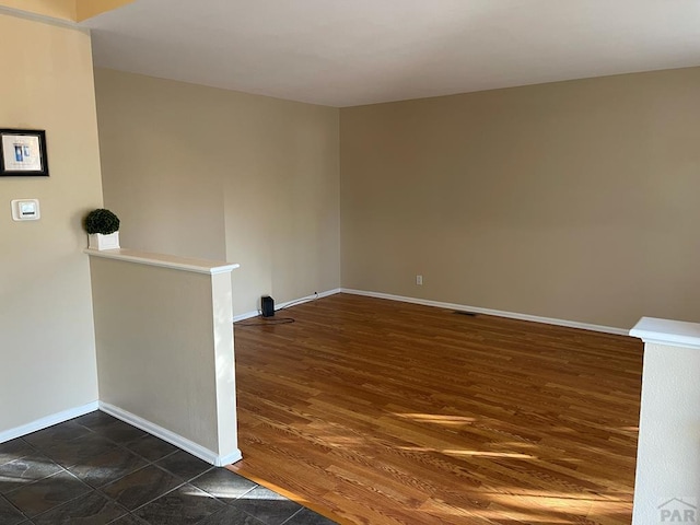 empty room with visible vents, baseboards, and dark wood-type flooring