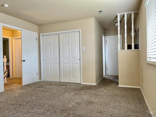 unfurnished bedroom with a closet, carpet, visible vents, and baseboards