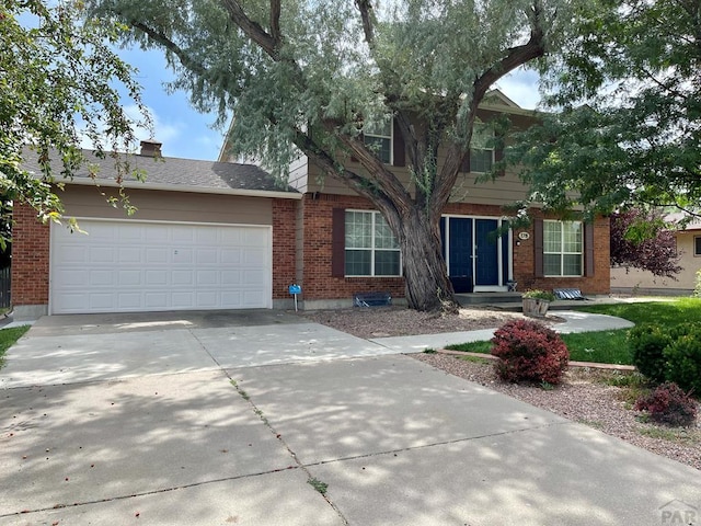 view of front of house featuring a garage, concrete driveway, and brick siding