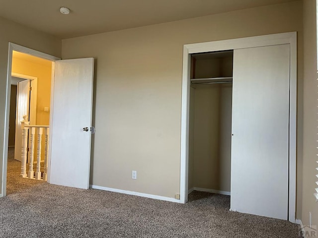 unfurnished bedroom with a closet, baseboards, and carpet flooring