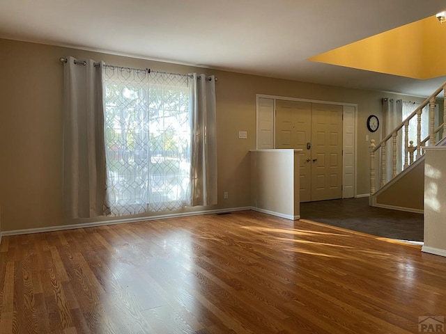 spare room featuring stairs, baseboards, and dark wood finished floors