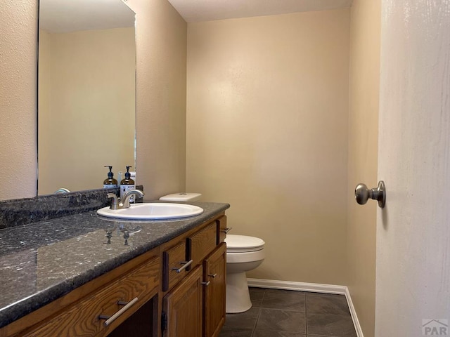 bathroom with baseboards, vanity, toilet, and tile patterned floors