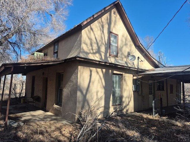 rear view of property with a carport and a patio area