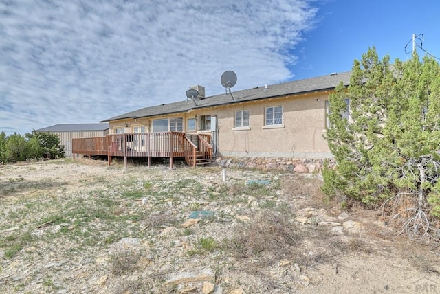 rear view of house featuring a wooden deck and stucco siding