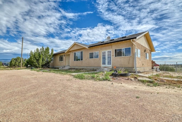 view of property exterior featuring stucco siding, fence, and french doors