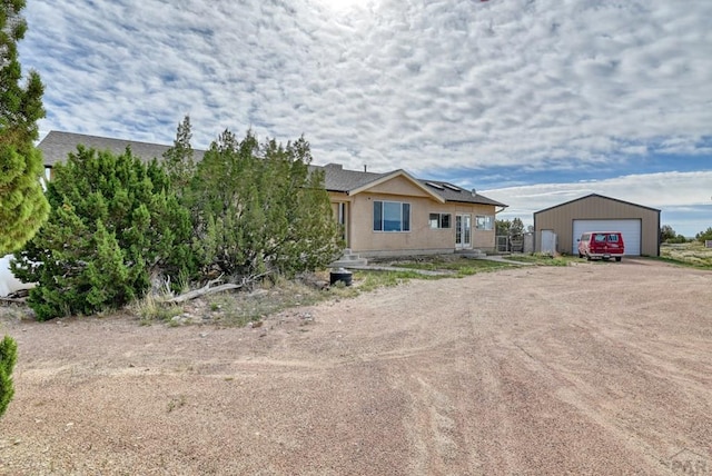 view of front facade featuring a garage, an outbuilding, and driveway