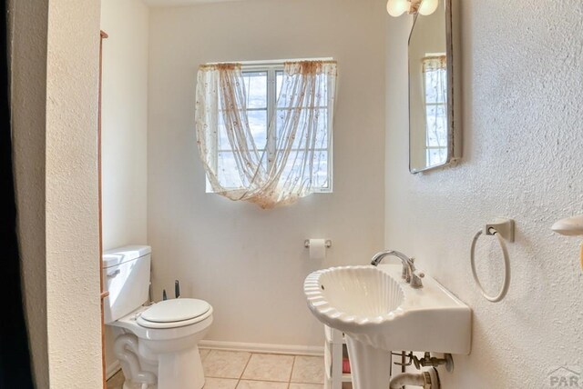 half bathroom featuring tile patterned flooring, toilet, and baseboards