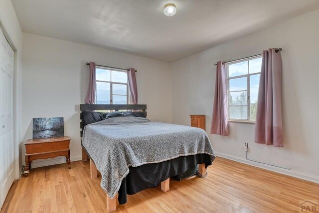 bedroom with a closet, light wood-style flooring, and baseboards