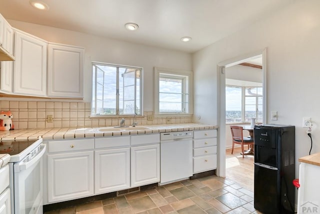 kitchen featuring white appliances, a sink, and white cabinets