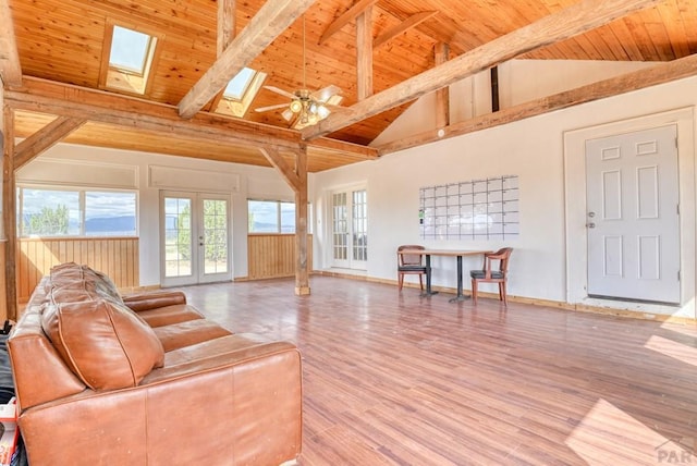 living area featuring wooden ceiling, a skylight, wood finished floors, french doors, and beamed ceiling