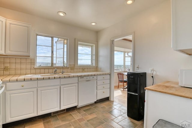 kitchen featuring white appliances, decorative backsplash, a sink, and white cabinets