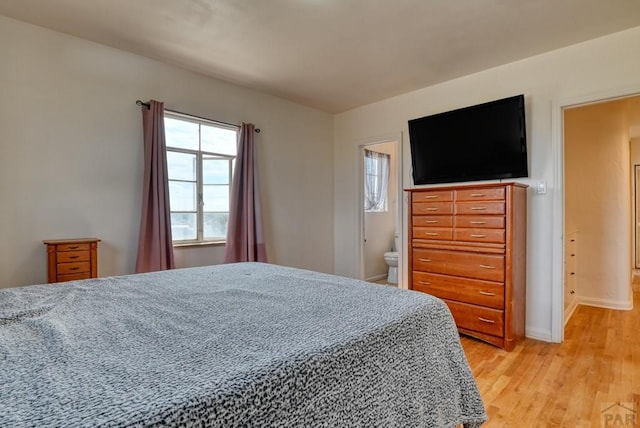 bedroom featuring baseboards, connected bathroom, and light wood finished floors