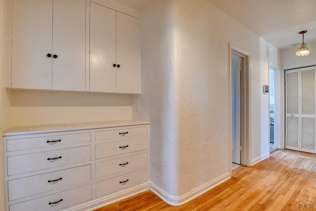 corridor with light wood-style flooring and baseboards