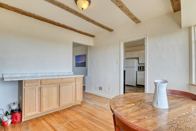 interior space featuring light wood finished floors, beam ceiling, and visible vents