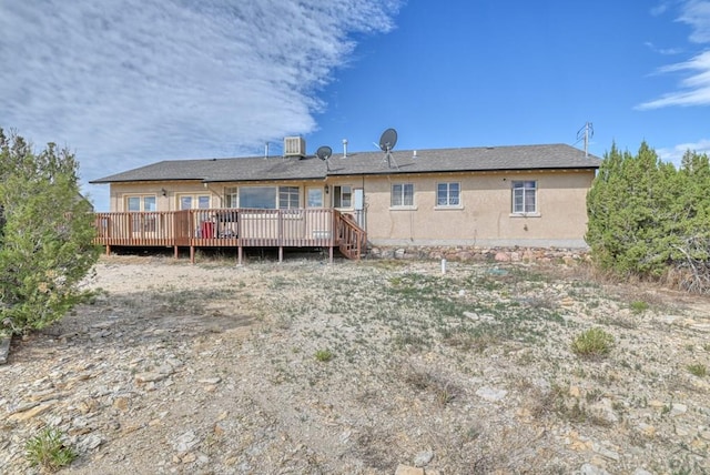 back of house featuring central AC unit, a deck, and stucco siding