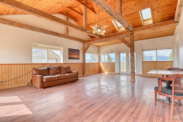 living room featuring a skylight, wooden ceiling, a wainscoted wall, and wood finished floors