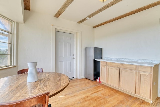 dining area with light wood-type flooring and beam ceiling