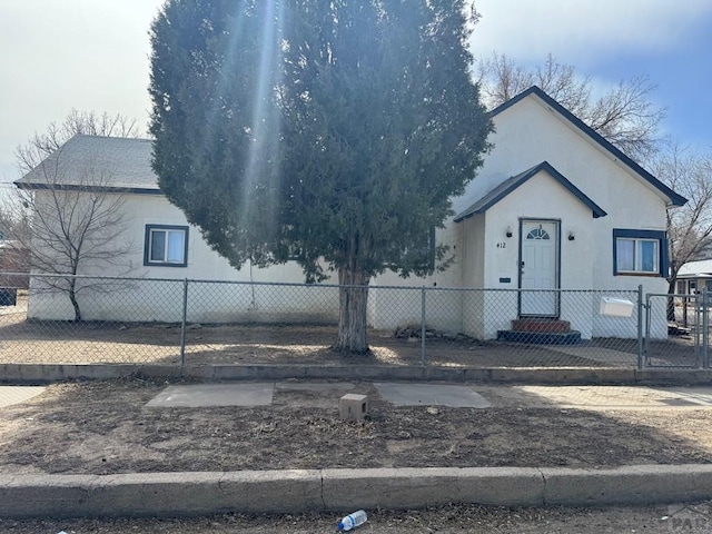 view of front of home featuring roof with shingles, a fenced front yard, and stucco siding