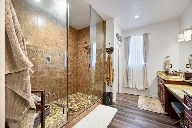 bathroom with vanity, recessed lighting, wood finished floors, a stall shower, and baseboards