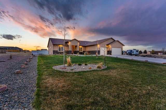 view of front of house featuring a garage, stucco siding, a lawn, stone siding, and concrete driveway