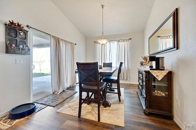 dining room with plenty of natural light, dark wood-style floors, baseboards, and lofted ceiling
