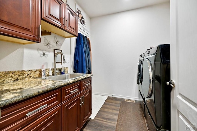 laundry area with dark wood finished floors, separate washer and dryer, wet bar, a sink, and cabinet space