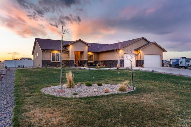 view of front facade with a yard, an attached garage, stone siding, stucco siding, and driveway