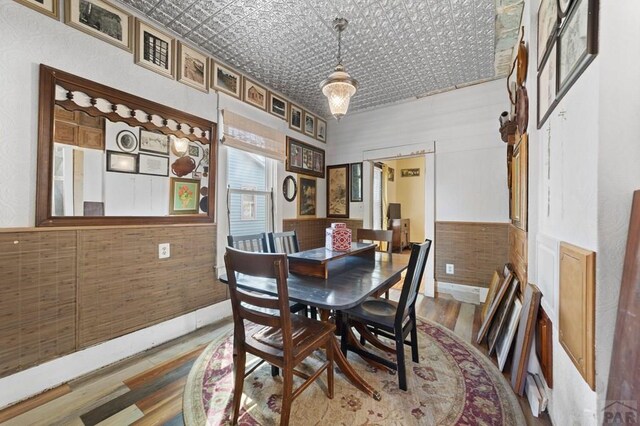 dining room with an ornate ceiling, wood finished floors, and wainscoting