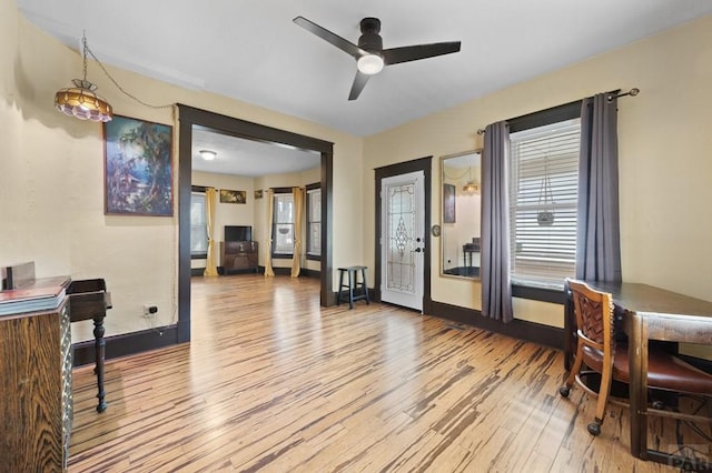 interior space featuring a ceiling fan, baseboards, and wood finished floors