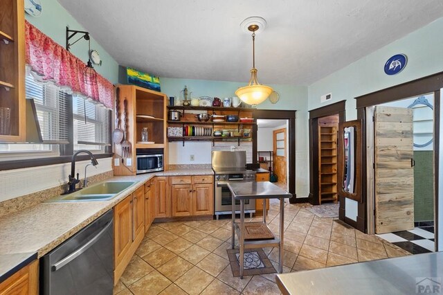 kitchen featuring pendant lighting, light tile patterned floors, stainless steel appliances, open shelves, and a sink