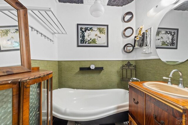 bathroom featuring wainscoting, a sink, tile walls, and a bathing tub