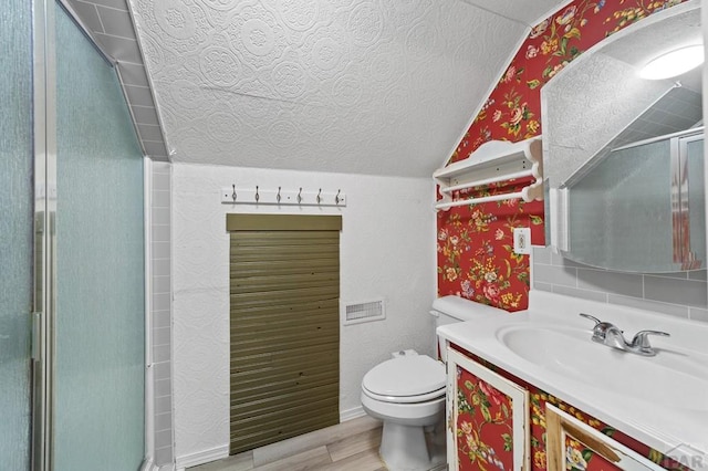 bathroom featuring lofted ceiling, toilet, wood finished floors, a textured ceiling, and a shower stall