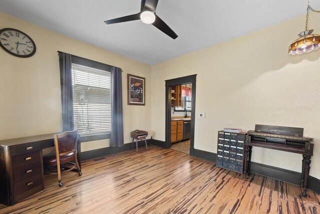 office space featuring a ceiling fan, baseboards, and wood finished floors