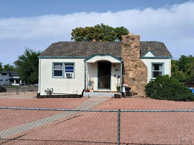 view of front of home featuring cooling unit, a shingled roof, fence, stucco siding, and a chimney