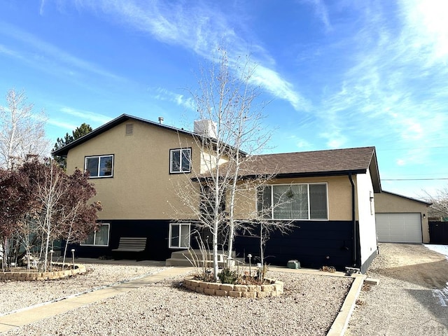 view of front of home featuring a garage, a chimney, and stucco siding