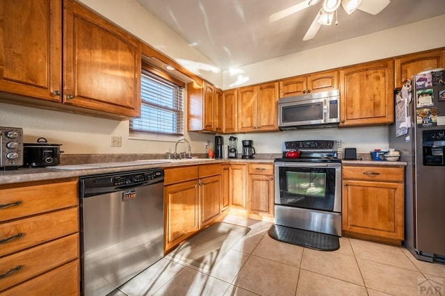 kitchen featuring light countertops, appliances with stainless steel finishes, light tile patterned flooring, and brown cabinets