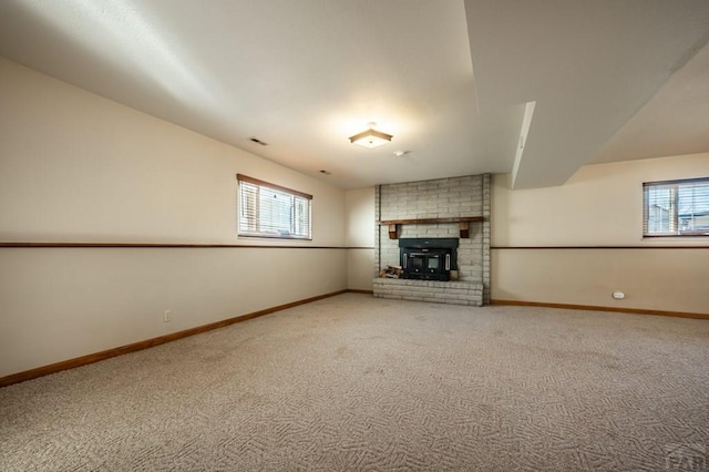 unfurnished living room with carpet, a fireplace, and baseboards