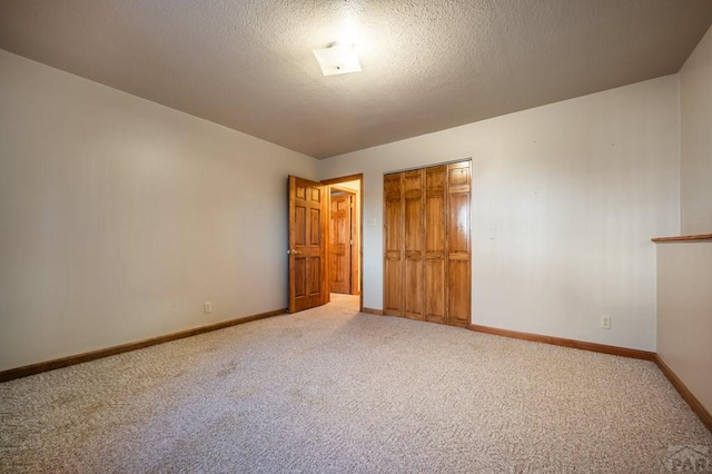 unfurnished bedroom with a textured ceiling, a closet, carpet, and baseboards