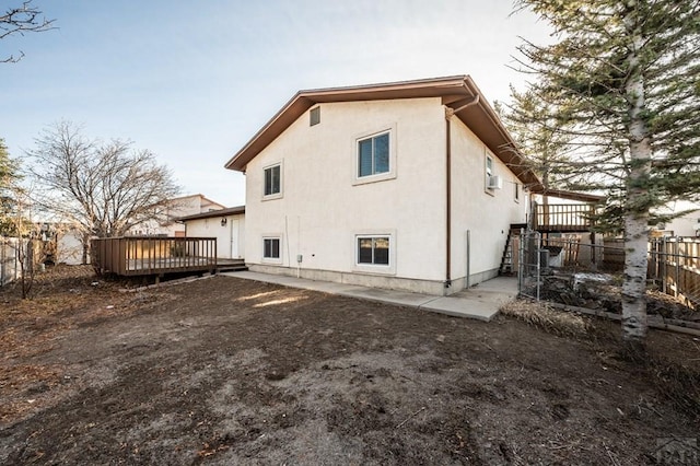 back of house featuring fence, a wooden deck, and stucco siding